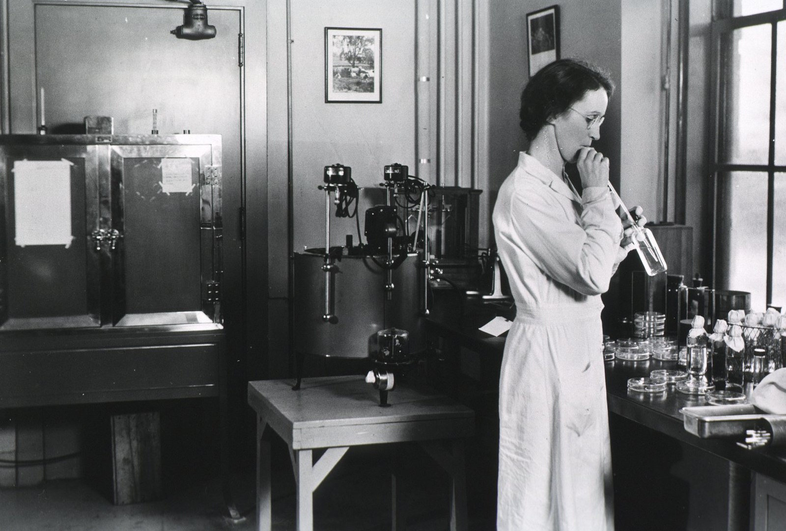 Historisches Foto: eine Person saugt eine Flüssigkeit mit dem Mund in eine Pipette an